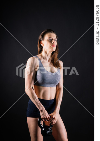 Young female doing swing exercise with a kettle bell. Fitness woman Young female doing swing exercise with a kettle bell. Fitness woman 112976058