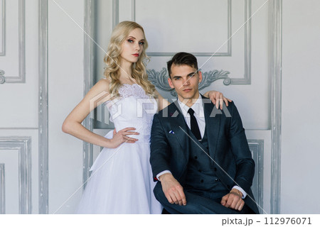 Cute wedding couple in the interior of a classic studio decorated. They kiss and hug each other. Cute wedding couple in the interior of a classic studio decorated. They kiss and hug each other. 112976071