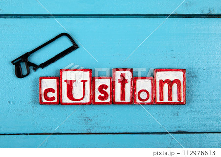 CUSTOM. Miniature saw on a blue wooden background. construction and carpentry concept 112976613