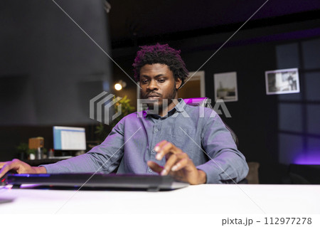Player using keyboard and mouse to play first person shooter videogame on PC, enjoying leisure time. Man in living room using high tech computer peripherals to destroy enemies 112977278
