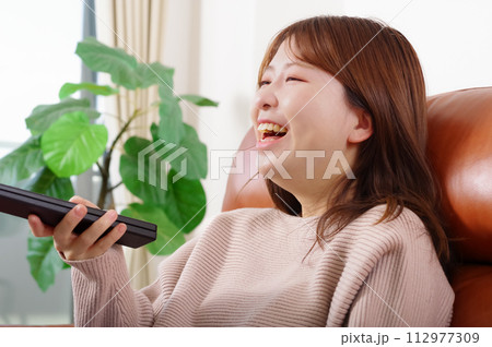 ソファーに座ってテレビを見る女性 112977309