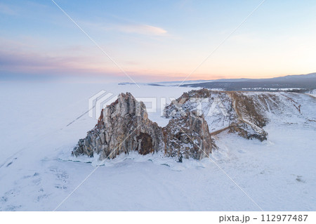 Aerial shot of a Shamanka rock on Olkhon island at sunset. Winter landscape. Popular touristic destination. Natural landmark. Panoramic view 112977487