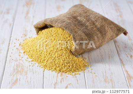 Raw grains of millet in sack on a light table, selective focus. Raw grains of millet in sack on a light table, selective focus. 112977571
