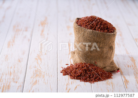 Raw red rice in sack on a light table, selective focus. Raw red rice in sack on a light table, selective focus. 112977587