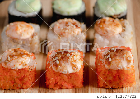 Set of sushi rolls on bamboo serving tray. Uramaki and futomaki roll Set of sushi rolls on bamboo serving tray. Uramaki and futomaki roll 112977822