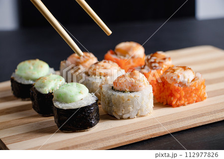 Set of sushi rolls on bamboo serving tray. Uramaki roll, chopsticks and soy sauce. Set of sushi rolls on bamboo serving tray. Uramaki roll, chopsticks and soy sauce. 112977826