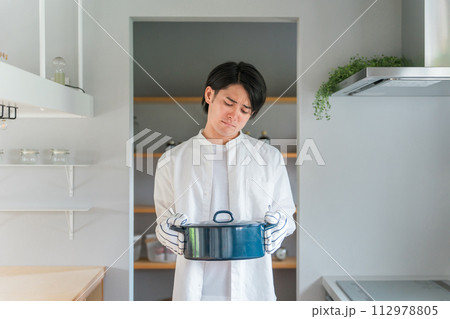 キッチンで鍋を持つ悩む男性・料理下手な夫・主夫・料理男子 112978805