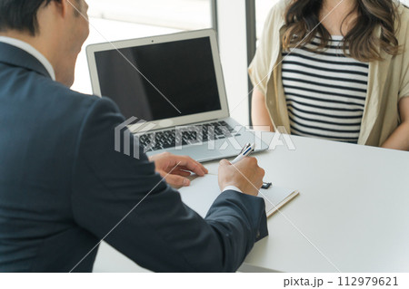 カウンセリングをするスーツ姿の男性ビジネスマンと顧客の女性(悪徳業者・詐欺師・詐欺被害・特殊詐欺) カウンセリングをするスーツ姿の男性ビジネスマンと顧客の女性(悪徳業者・詐欺師・詐欺被害・特殊詐欺) 112979621