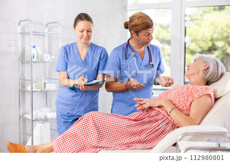 Female nurse and male doctor carries out survey of mature female patient about allergic reactions Female nurse and male doctor carries out survey of mature female patient about allergic reactions 112980801