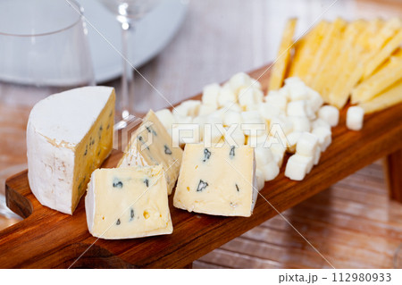 Assorted cheeses served on board to table Assorted cheeses served on board to table 112980933