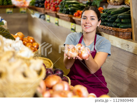 Young woman selling onions in shop 112980940