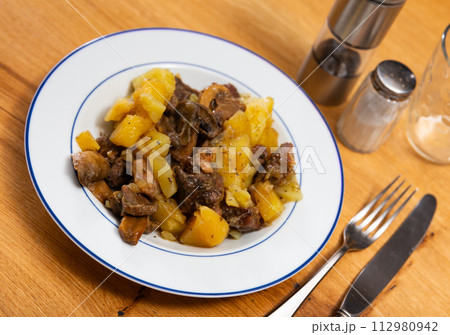 There is portion of stewed veal with vegetables in deep plate 112980942