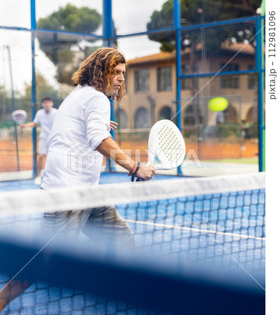 Caucasian man playing paddle tennis on padel court Caucasian man playing paddle tennis on padel court 112981096