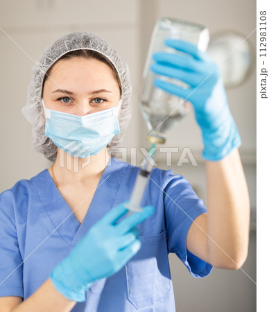 Nurse fills syringe with injection solution 112981108