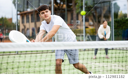 Male player ready to hits the ball while playing padel on hard court 112981182