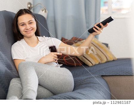 Woman drinking wine watching TV at home 112981187
