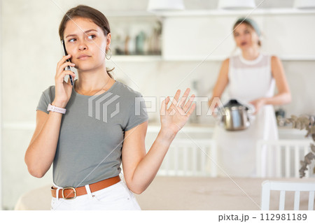 Girl silently listens to woman’s reproaches and looks at phone 112981189