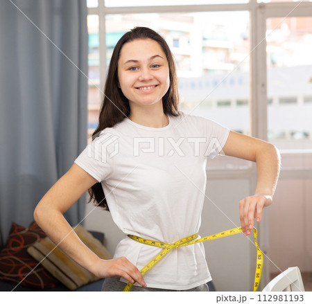 Portrait of woman taking measurements of body 112981193