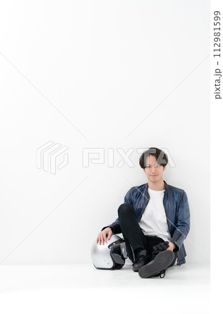 ヘルメットを持って座る男性ライダー 112981599