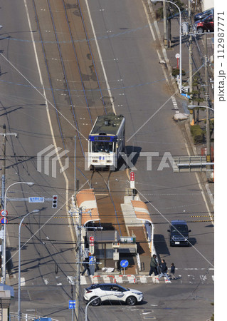 【縦構図・人物ナンバーロゴレタッチ済み】函館市電　谷地頭電停に進入、出発の様子 112987771