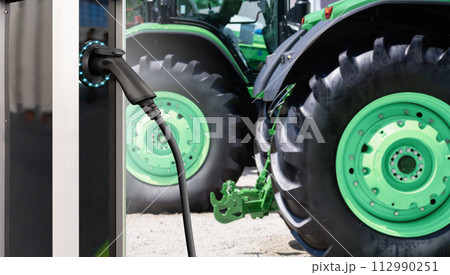 Electric vehicles charging station on a background of agricultural tractors. Concept 112990251