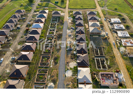 Construction of a suburban neighborhood of cottages. Aerial view. 112990890
