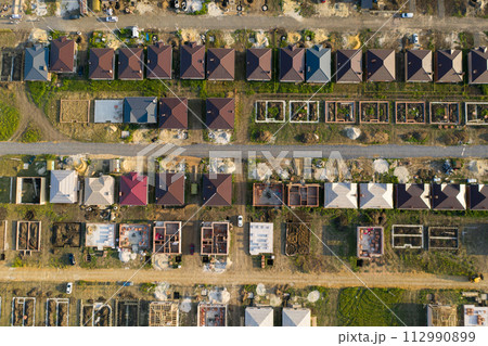 Construction of a suburban neighborhood of cottages. Aerial view. Construction of a suburban neighborhood of cottages. Aerial view. 112990899