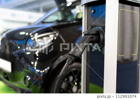 Electric car is charged from a charging station that takes energy from solar panels. Close up.. Electric car is charged from a charging station that takes energy from solar panels. Close up.. 112991074