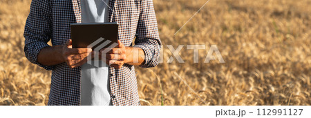 Farmer with digital tablet on an agricultural field. Close up. Smart farming and digital agriculture. 112991127