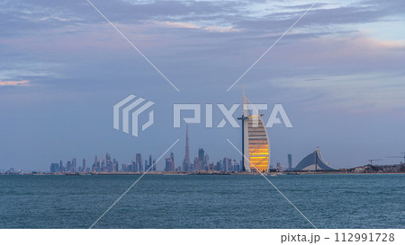 Dubai skyline with Burj Al Arab hotel during sunset and day to night timelapse. Dubai skyline with Burj Al Arab hotel during sunset and day to night timelapse. 112991728