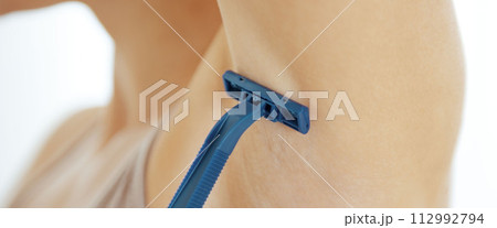 Closeup on young woman shaving armpit Closeup on young woman shaving armpit 112992794