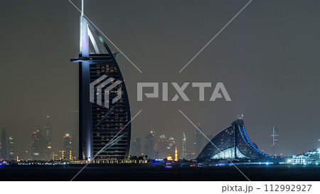 Skyline of Dubai at night timelapse with Burj al Arab in foreground in Dubai, United Arab Emirates 112992927