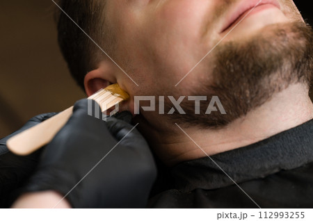 Hair removal procedure in a barbershop. Ear hair wax removal. 112993255