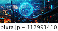 Earth from holographic graphics showing global network connectivity on human hand and blurred city background in the evening in a bird's eye view. 112993410