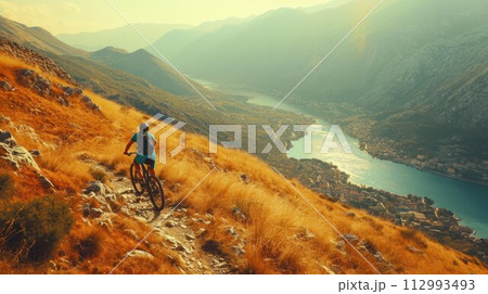Cyclist Riding the Bike in the Beautiful Mountains Down the Rock on the Sunrise Sky Background. Extreme Sport and Enduro Biking Concept 112993493