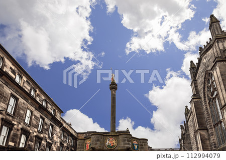 Historic Mercat Cross with golden unicorn stands in Edinburgh Parliament Square against buildings Historic Mercat Cross with golden unicorn stands in Edinburgh Parliament Square against buildings 112994079