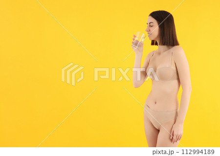 Slim girl in underwear drinks water from a glass. Slim girl in underwear drinks water from a glass. 112994189