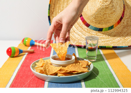 Nachos with sombrero and tequila on a light background 112994325