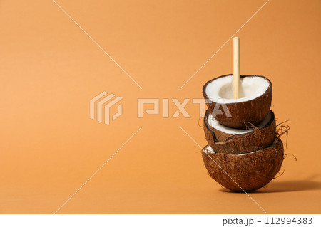 Coconuts with straw on beige background, space for text Coconuts with straw on beige background, space for text 112994383
