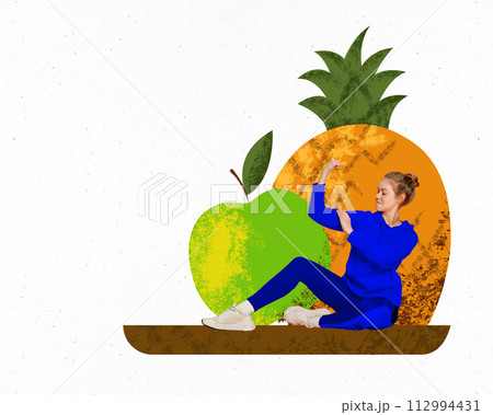 Young woman in headphones sitting around apples and pineapple, showing muscles, training on white background. Creative conceptual collage. 112994431