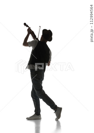 Male silhouette, talented young musician playing violin isolated on white background. Black and white image. 112994564