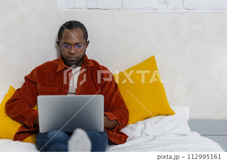 Dark-skinned young man with a laptop working at home 112995161