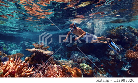 attractive young man snorkels in the ocean and observes the coral world, free diver in the sea, coral reefs in the Maldives 112995320