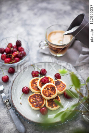 Cottage cheese pancakes with fresh cherry and coffee for breakfast 112996057