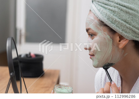 Skin's Delight: She graces her face with a moisturizing mask, nurturing her skin's health and beauty at home. Skin's Delight: She graces her face with a moisturizing mask, nurturing her skin's health and beauty at home. 112996286