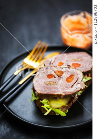 Gourmet sandwich with roasted pork (ham), pickled cucumber, lettuce, sauce, artisan bread 112996703
