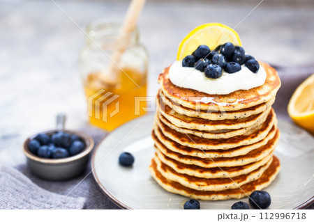 Stack of freshly prepared lemon poppy seed pancakes topped with sour cream and blueberries 112996718