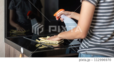 Asian woman cleaning the table surface with towel and spray detergent Asian woman cleaning the table surface with towel and spray detergent 112996970