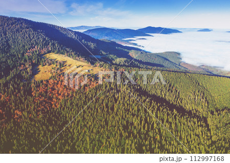 Aerial view of mountains above the clouds in the misty morning. View of the mountains in autumn. Beautiful nature landscape. Carpathian mountains. Ukraine Aerial view of mountains above the clouds in the misty morning. View of the mountains in autumn. Beautiful nature landscape. Carpathian mountains. Ukraine 112997168