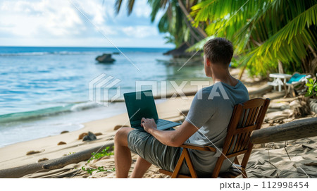 Man Working on Laptop at Tropical Beach Man Working on Laptop at Tropical Beach 112998454